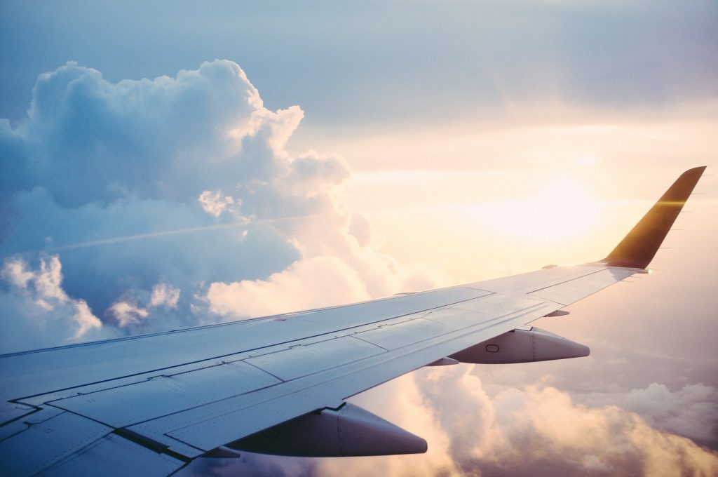 Ala di aeroplano con nuvole e sole sullo sfondo
